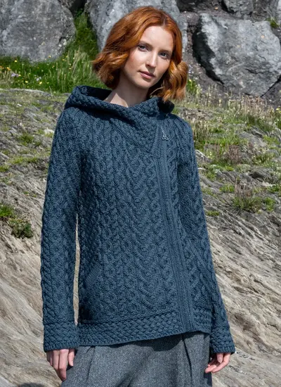Red headed model standing in rocky area wearing a blue Aran biker hoodie